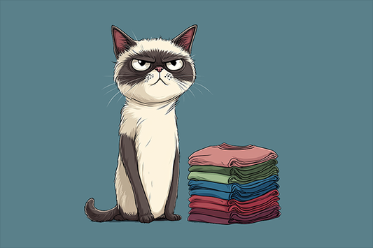 Grumpy cat sitting next to a stack of t-shirts